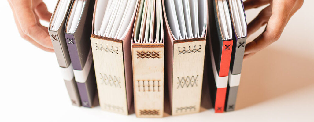 Stack of handmade books, hands on either side