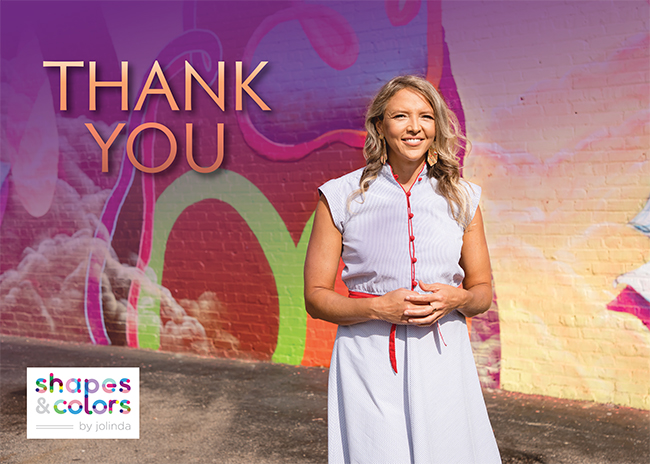 Image of Jolinda smiling in front of a mural with the words "Thank You" in the top left corner and the Shapes & Colors logo in the bottom left