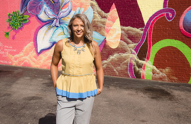 Jolinda standing in front of colorful mural with a smile.