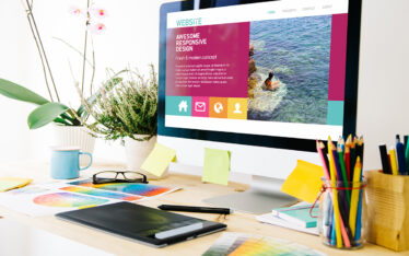 Colorful office desk with desktop computer, tablet and colored pencils, responsive web design in the monitor